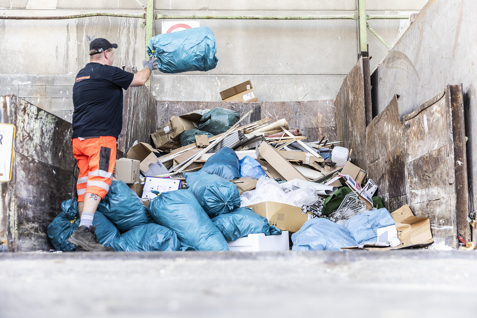 Baumgärtner Wertstoff Ein Mann wirft einen Abfallsack auf einen Müllhaufen
