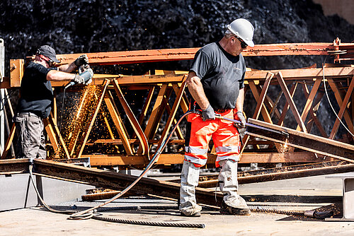 Schweißarbeiten bei Baumgärtner Zwei Mitarbeiter von Baumgärtner Recycling schweißen an einem rostigen Strahlträger